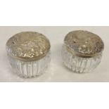 A pair of silver topped glass pots with Art Nouveau style detailed lids.
