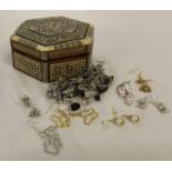 A small bone and mother of pearl trinket box containing a collection of costume jewellery earrings.