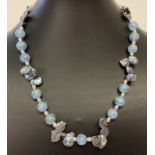 A blue rock crystal and freshwater peacock pearl necklace with silver tone magnetic barrel clasp.