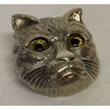 A silver pendant brooch in the shape of a cats head with glass set eyes.