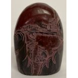 A carved red and black Chinese soapstone seal depicting fishermen.