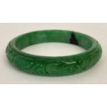 A green jade bangle with carved detail to outer surface.