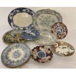 A collection of antique and vintage ceramic plates and meat plates in varying sizes and conditions.