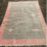 A modern Aztec design large rug in green ground, orange boarder and fringed ends.