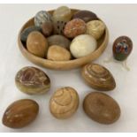 A wooden bowl containing a collection of wooden and natural stone eggs in varying sizes.