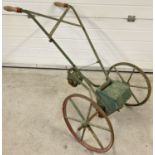 A vintage push seed drill with cast iron wheels and wooden handles. Painted red and green.