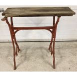 A vintage painted cast iron treadle sewing machine base with rustic wooden top.