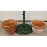 2 terracotta plant pots together with a heavy cast metal parasol stand painted green.