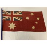A vintage British Empire Australian red ensign flag on a modern wooden pole.
