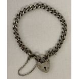 A vintage silver charm bracelet with padlock clasp and safety chain.