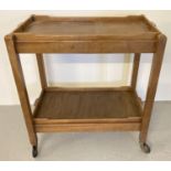 A vintage collapsible wooden tea trolley with removeable butlers trays.