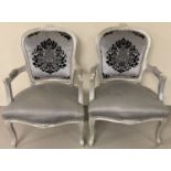 A pair of Louis XV style wooden framed arm chairs, painted silver.
