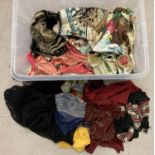 A box of mixed vintage pieces of material, some embroidered, shawls and scarves.
