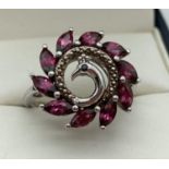 A modern design silver dress ring in the design of a peacock set with 10 marquise cut rhodolite