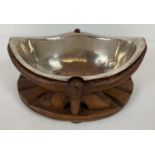 A vintage silver plated copper boat shaped dish in an ornate carved wooden stand.