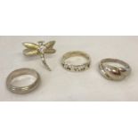4 silver and white metal dress rings. Comprising: band ring, a dragonfly ring set with a clear