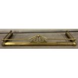 A vintage brass extending fire fender with finial, rail and scroll detail.