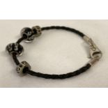 A silver and black plaited leather bracelet by Silverado, together with 4 charm beads. Makers name