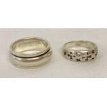 2 silver band style rings. A spinner ring together with a band with pierced crosses and stars