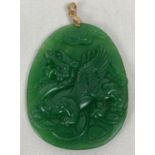 A carved jade pendant, with gold coloured bale, designed with Chinese dragon carving to one side.