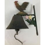 A painted cast iron wall hanging garden bell with Cockerel and flower detail.