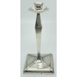 An Arts & Crafts silver candlestick with studded detail, square shaped base & circular bobeche.
