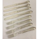 A set of 4 antique white metal knives and forks with floral and shell decoration to handles.