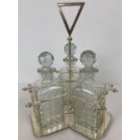 A silver plated triple decanter stand tantalus with 3 cut glass decanters. Central screw in stem