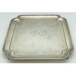 An Art Deco square shaped silver salver raised on 4 feet with stepped design to rim. Engraved to
