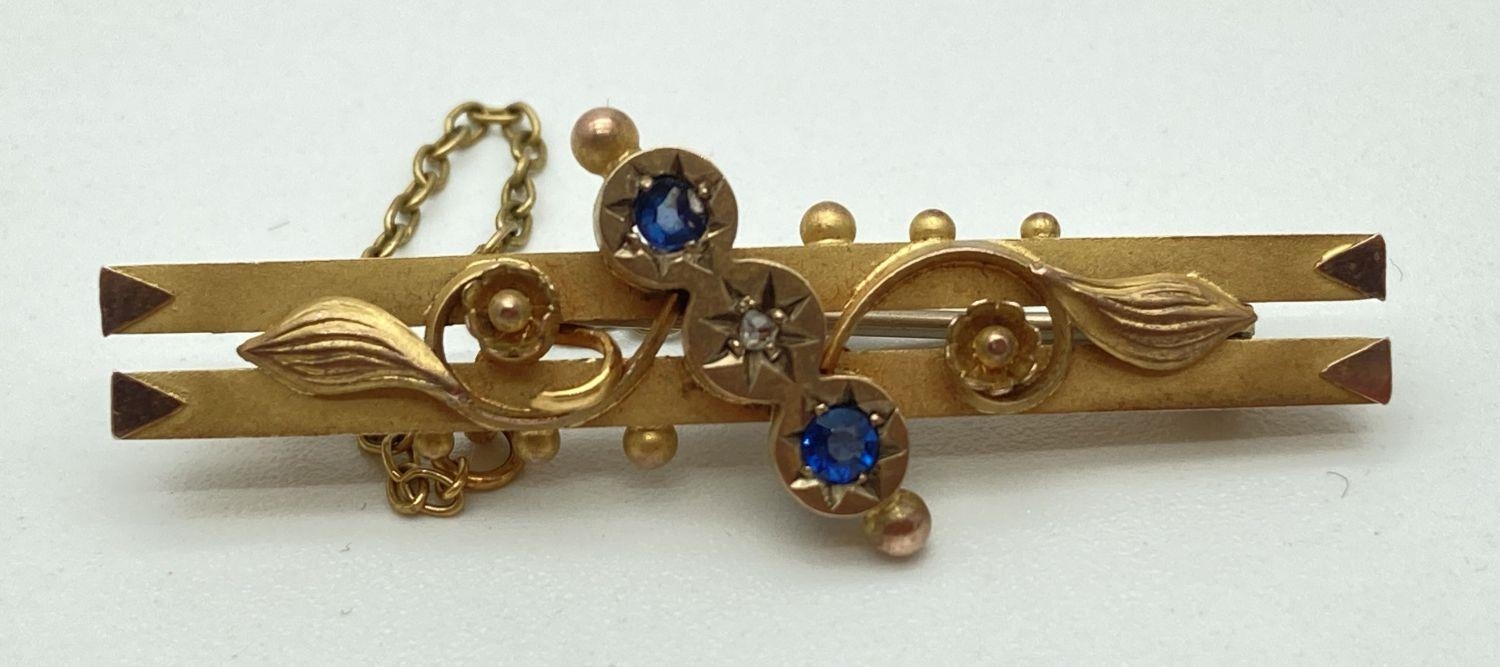 An Edwardian 9ct gold floral design bar brooch set with a small round cut diamond and 2 small