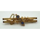 An Edwardian 9ct gold floral design bar brooch set with a small round cut diamond and 2 small