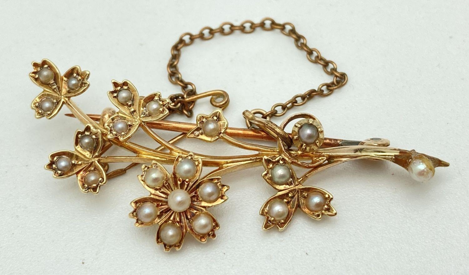 A vintage 15ct gold and seed pearl floral spray brooch with safety chain. Stamped 15ct to rear of