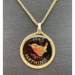 A 1945 farthing that has been coloured and enamelled, set in a gold tone pendant mount on a gold