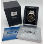 A Seiko 5 sports automatic wristwatch with green face and bezel. Stainless steel strap and