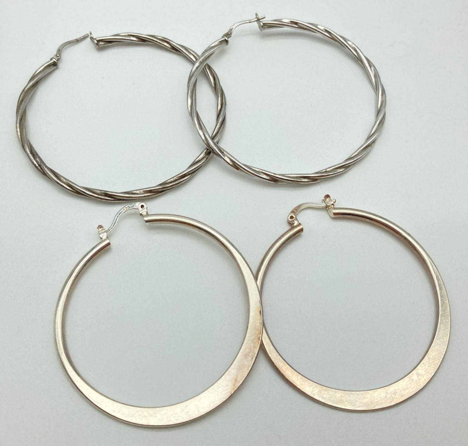 2 pairs of large silver hoop earrings. A pair of plain hoops together with a pair of twist design