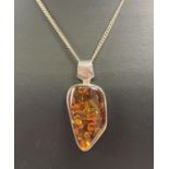 A modern design silver and amber pendant on a 18 inch curb chain with spring clasp. Pendant bale and