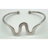 A white metal modern wave design torque style bangle.