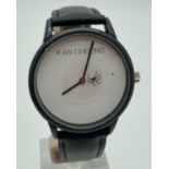 A Spider wristwatch by Kan Cheong. White face with black hour and minutes hand. Seconds hand is a