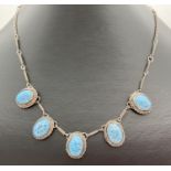 A vintage white metal necklace set with 5 oval mottle patterned blue stones. Approx 18 inches long.