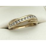 A 9ct gold, ¼ct diamond dress ring in crossover design set with 11 small round cut diamonds. Full