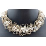 A bespoke made collar style necklace made from white metal wires in a floral design with aurora
