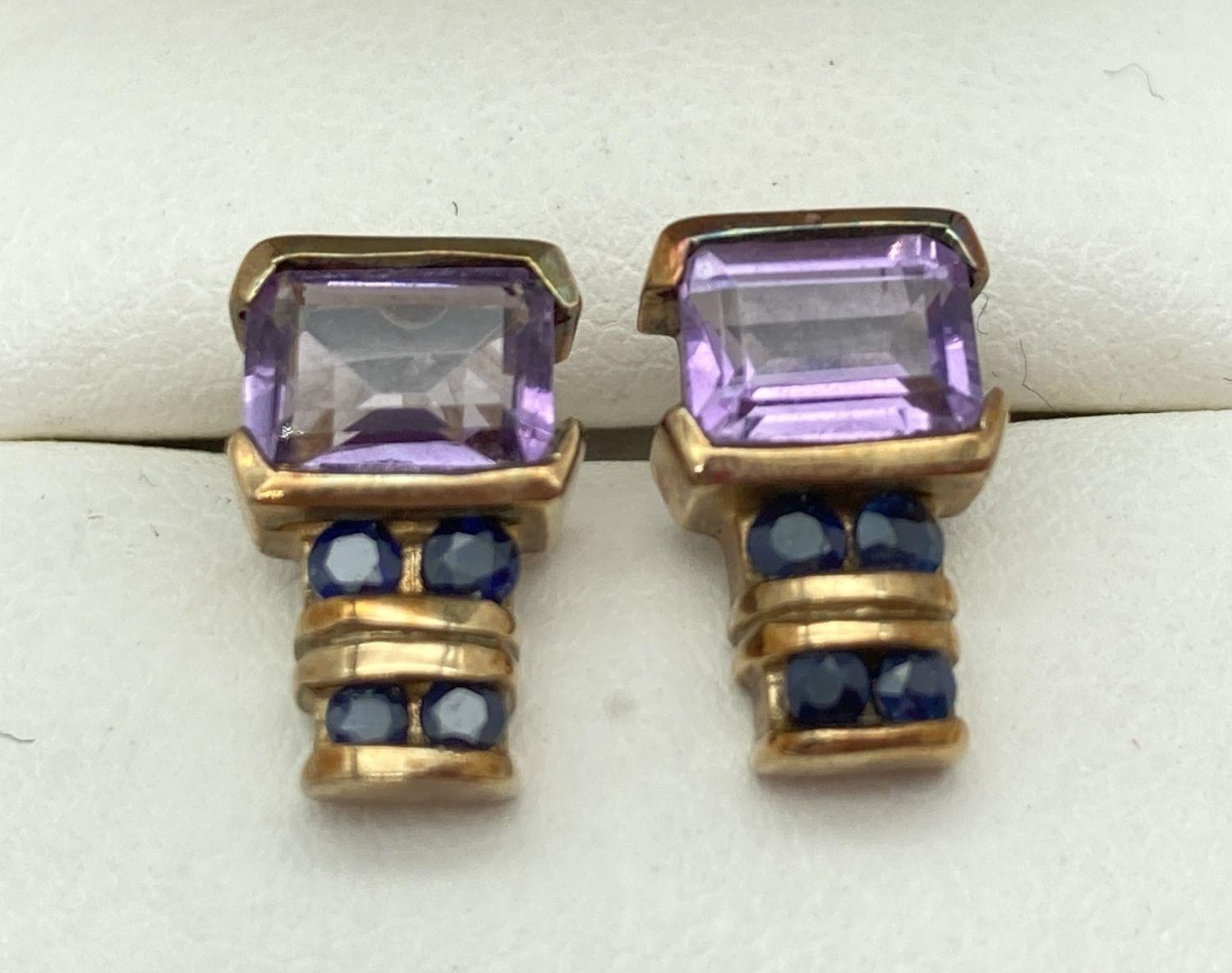 A pair of 9ct gold, amethyst and sapphire stud style earrings. Each earring set with a square cut