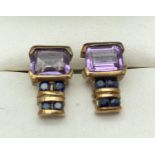 A pair of 9ct gold, amethyst and sapphire stud style earrings. Each earring set with a square cut