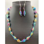 A faceted iridescent lustre glass beaded necklace with matching drop earrings. Necklace has silver