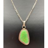 A modern design green stone set pendant on a 22 inch silver Figaro style chain with spring clasp.