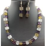 A modern design square glass bead necklace and matching drop earrings. Purple, clear and olive green