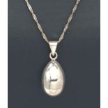 A silver egg shaped chiming pendant on an 18 inch Singapore style chain. Bale to pendant marked 925.