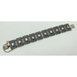 A vintage style silver bracelet with 10 lattice style square links each set with a baguette cut