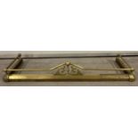 A vintage extending brass fire fender with finial, rail and scroll detail.