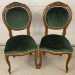A pair of Victorian style balloon backed wooden dining chairs with green velvet upholstery. Carved